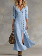Front view of a woman in a pale blue linen maxi dress with V-neckline, button-front detail and layered necklace