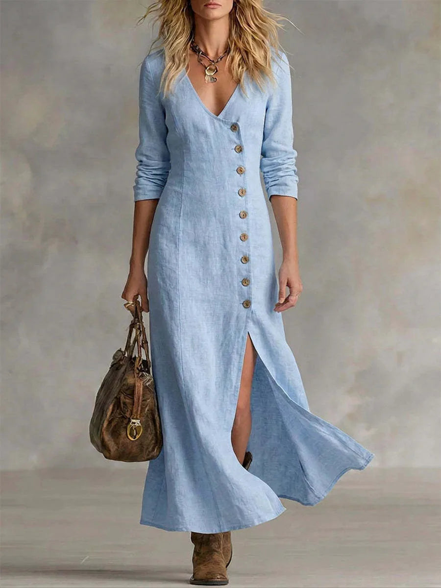 Front view of a woman in a pale blue linen maxi dress with V-neckline, button-front detail and layered necklace
