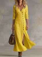 Woman walking in a yellow linen maxi dress with deep V-neck and front button placket
