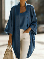 Woman walking in a mid-blue chambray kimono cardigan with raw-edge lapel, worn open over a matching camisole and white jeans