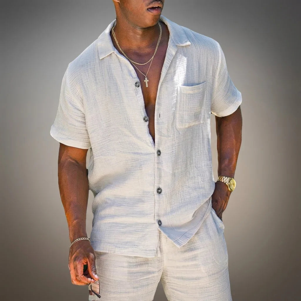 Close-up of a man wearing an open white textured linen short-sleeve shirt with a chest pocket and matching shorts