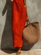 Detail shot of the straight-cut linen maxi dress skirt and hemline, worn with tan leather mule sandals and a straw bag