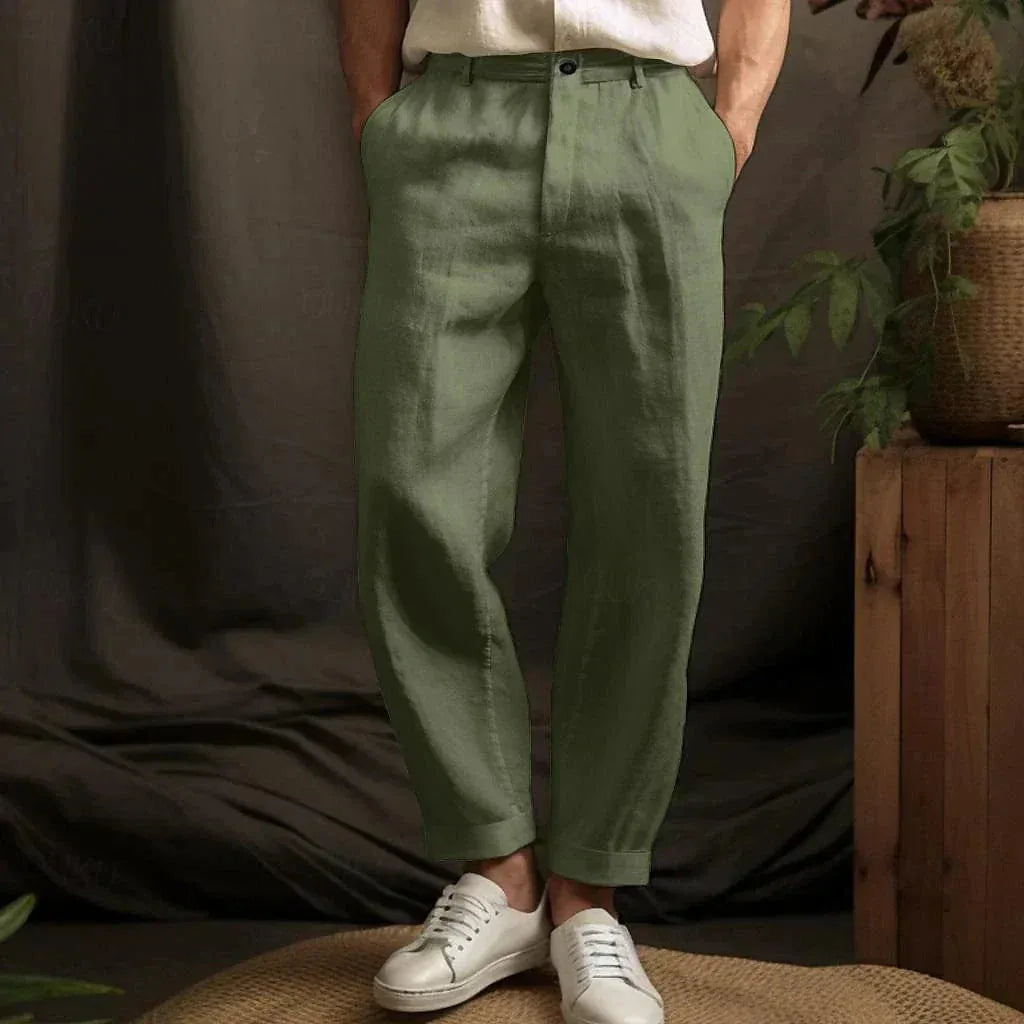 Front view of olive green linen tapered pants with a cuffed hem, styled with white sneakers and a linen top.