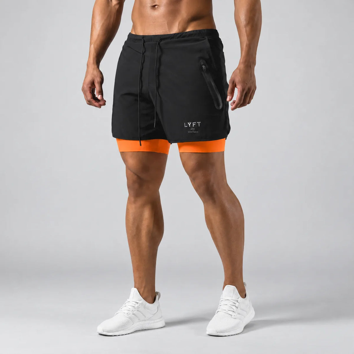 Front view of man wearing black 2-in-1 training shorts with orange compression liner and zip pocket