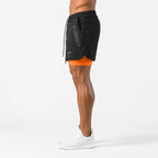 Side profile of black shorts with zip side pocket, drawstring waist and orange liner underneath