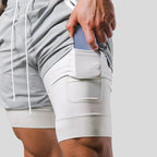 Close-up of hand placing a phone into the thigh pocket of the light grey compression liner