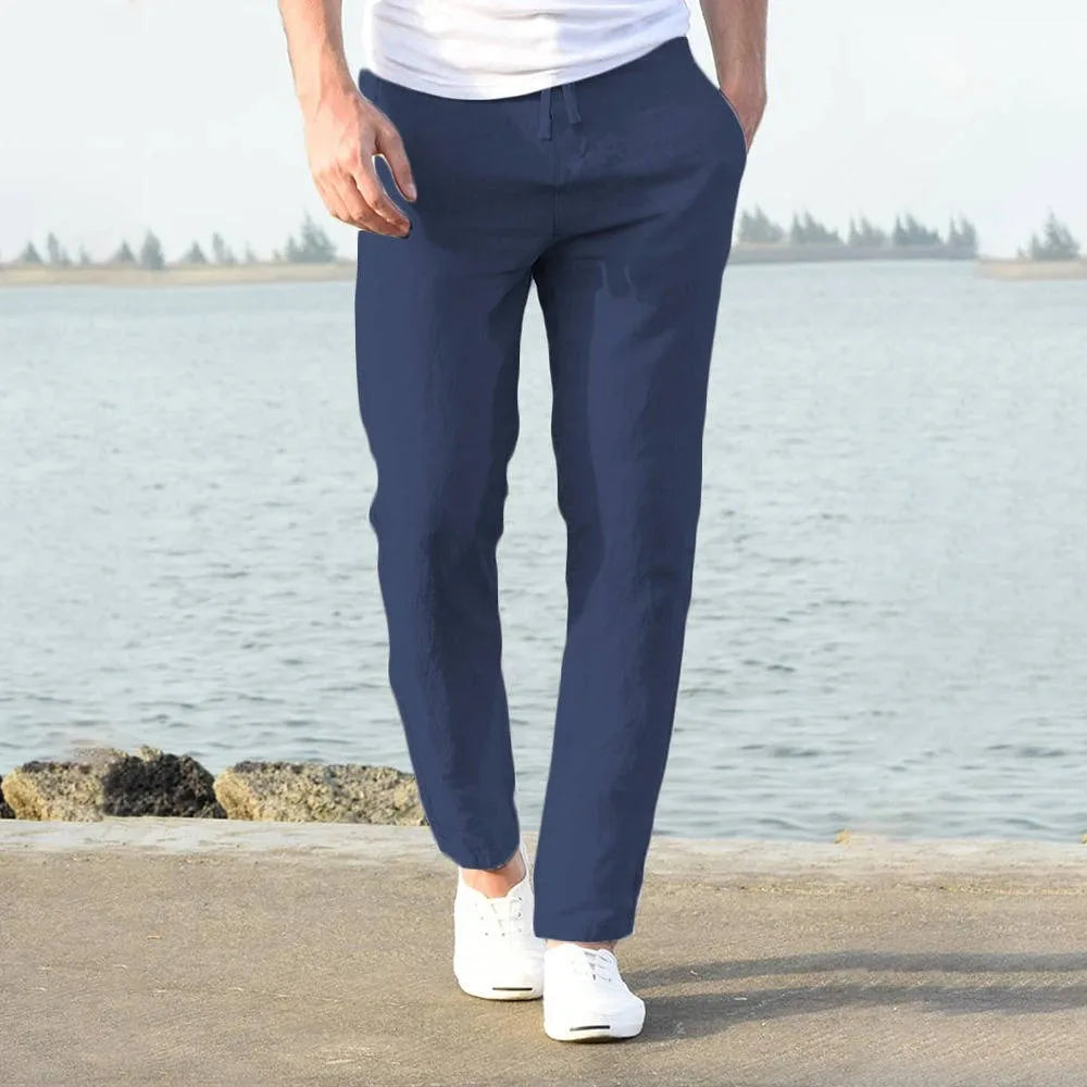 Close view of light khaki linen pants ankle hem resting above white sneakers