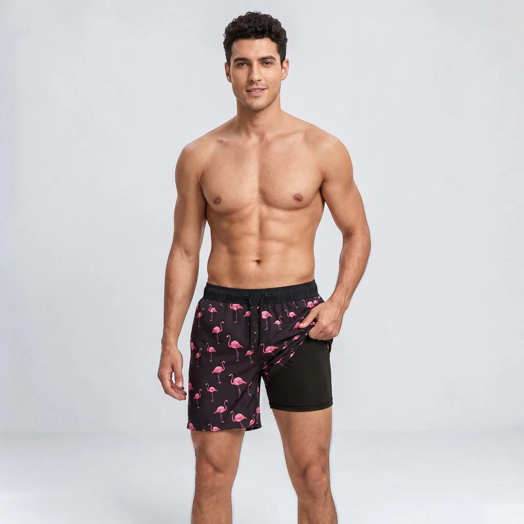 Man wearing black swim shorts with an allover pink flamingo print and matching black compression liner