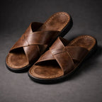 Side view of a pair of brown faux-leather crossover slide sandals with a thick black contrast sole