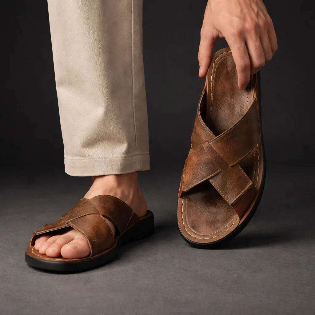 Model wearing brown crossover slide sandals, holding one sandal to show the cushioned footbed