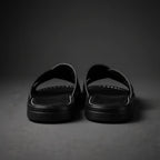 Front corner close-up of black sandals highlighting the round toe shape and ridged sole edge