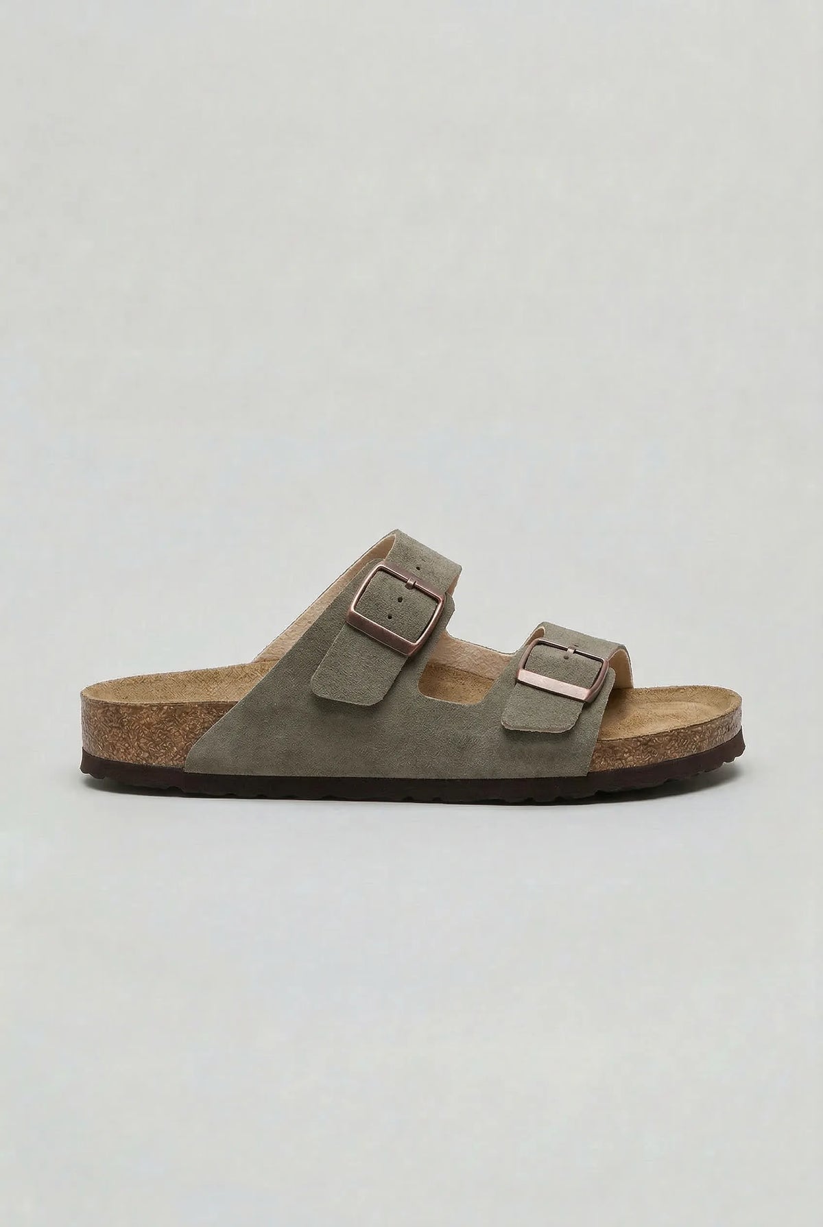 Side view of a dusty green suede two-strap sandal with brown outsole and bronze-tone buckles