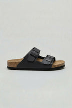 Side profile of a black two-strap buckle sandal with matching black sole and dark hardware