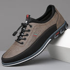 Three-quarter angle of stone grey leather sneaker with black accents and toggle lace closure