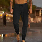 Man walking at dusk wearing black linen-blend drawstring pants with tapered, gathered ankle cuffs