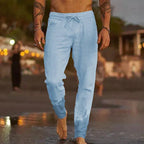 Man walking at dusk wearing light blue linen-blend drawstring pants with gathered ankle cuffs