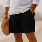 Black linen-blend shorts with drawstring tie and side pockets, worn with a rolled-sleeve white shirt