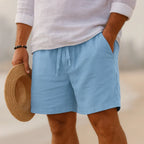 Sky blue linen-blend shorts with drawstring tie, paired with a white shirt and straw boater hat