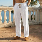 Front view of white linen drawstring pants paired with tan suede loafers against a balustrade backdrop