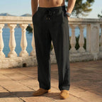 Black linen drawstring pants shown from the waist down on a sunlit stone terrace