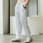 Side view of white linen pants showing drawstring waist and straight leg cut on model