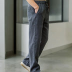 Side profile of charcoal grey linen pants in motion showing wide leg flow and pocket seam