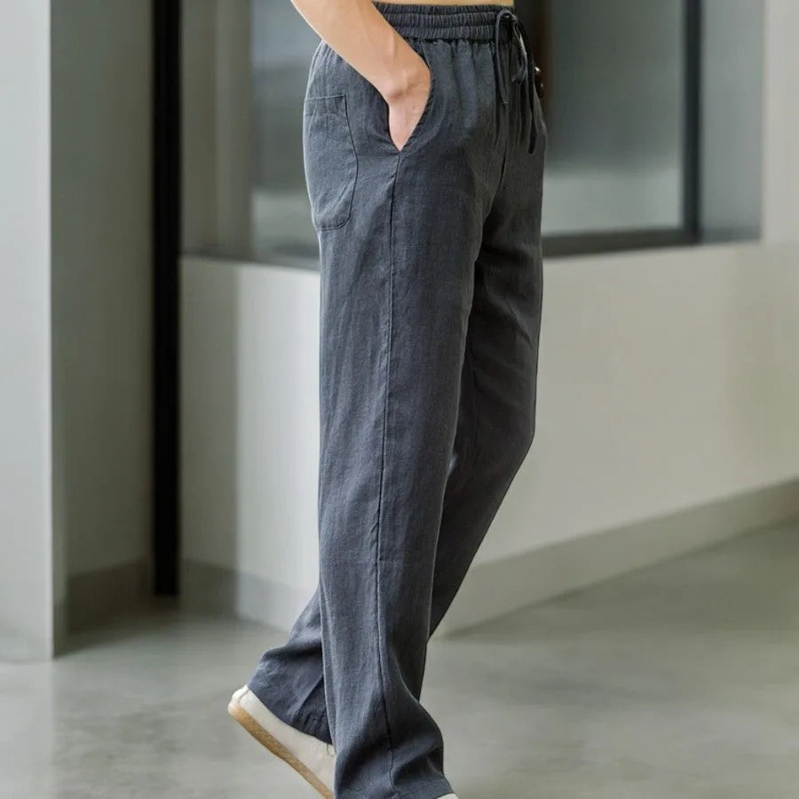 Side profile of charcoal grey linen pants in motion showing wide leg flow and pocket seam