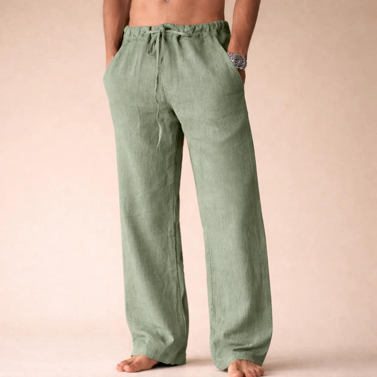 Back view of sage green linen drawstring trousers with side pocket, relaxed straight-leg fit on a barefoot model.