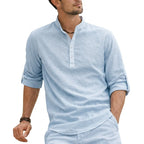 Close-up of a light blue grandad collar shirt with half button placket, sleeve folded and cuffed with button tab