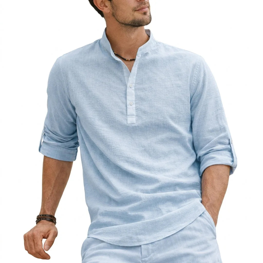 Close-up of a light blue grandad collar shirt with half button placket, sleeve folded and cuffed with button tab