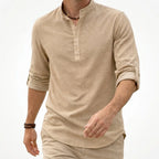 Man walking in a beige grandad collar shirt with half placket, rolled sleeve with button tab, matching beige pants