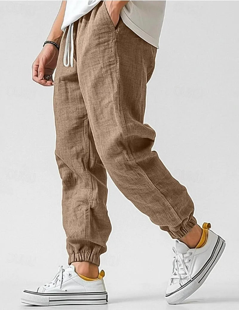 Side view of khaki brown linen jogger trousers showing tapered elastic ankle cuff and relaxed wide leg