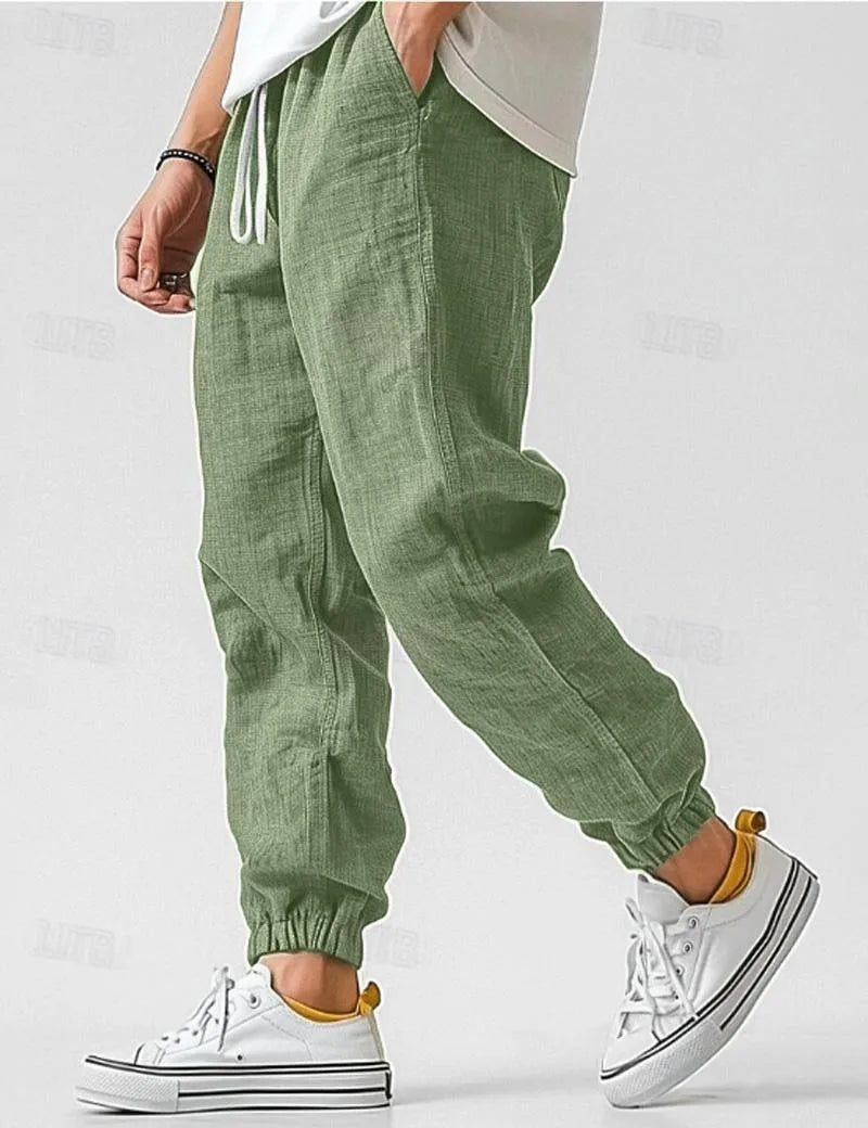 Man walking in sage green linen jogger pants with visible woven texture and drawstring waistband detail