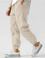 Beige linen jogger pants shown in motion, highlighting the relaxed fit and tapered elastic ankle cuff