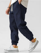 Navy linen jogger pants in profile view, showing the loose tapered leg and elastic cuffed ankle