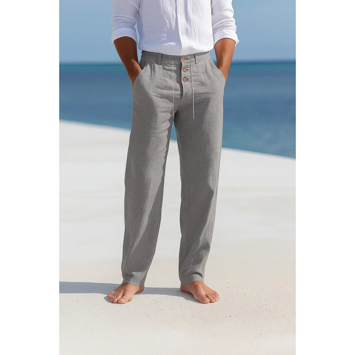 Man on a beach wearing grey linen trousers with a white linen shirt, front view