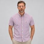 Front view of a man wearing a short-sleeve check shirt in red, navy and white with a buttoned chest pocket