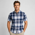 Front view of a man wearing a navy, blue and white plaid short-sleeve shirt with buttoned chest pocket