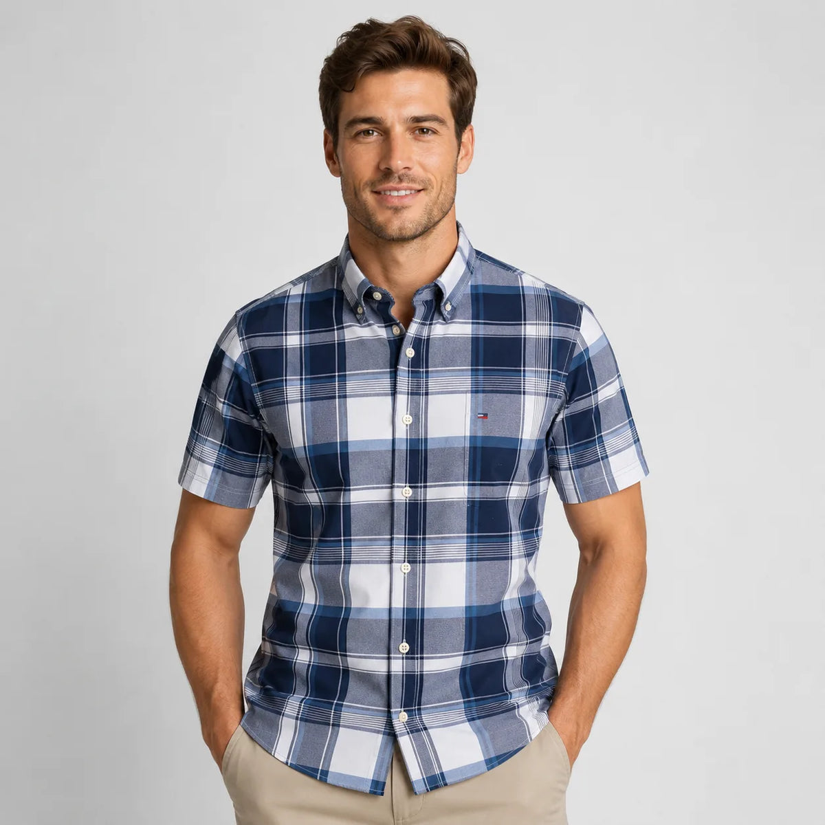 Front view of a man wearing a navy, blue and white plaid short-sleeve shirt with buttoned chest pocket