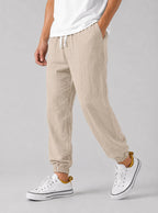 Side view of beige textured linen jogger trousers with drawstring waist and elasticated cuffed ankle