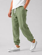 Side view of sage green textured linen jogger trousers with drawstring waist and relaxed wide leg