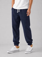 Front angled view of navy blue linen jogger trousers with white drawstring and elasticated ankle cuff
