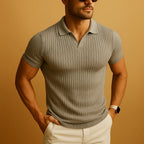 Man in a light grey ribbed knit polo shirt with open V-neck collar, paired with white trousers and sunglasses