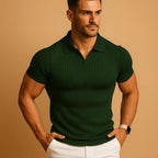 Man wearing a dark green ribbed knit polo with open collar, short sleeves and a smart watch, white trousers below