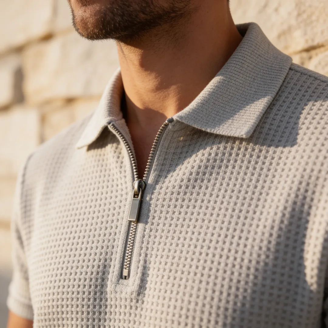 Close-up of the quarter-zip collar detail on a grey waffle-textured knit polo shirt