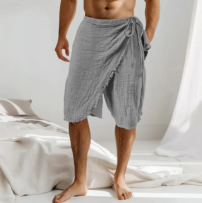 Man wearing a grey crinkle cotton wrap sarong tied at the waist, tulip hem falling just below the knee.