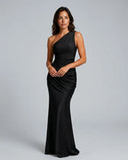 Woman in black one-shoulder satin maxi dress with draped waist, standing front-on in studio