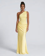 Front view of pale yellow one-shoulder satin maxi dress styled with pearl drop earrings