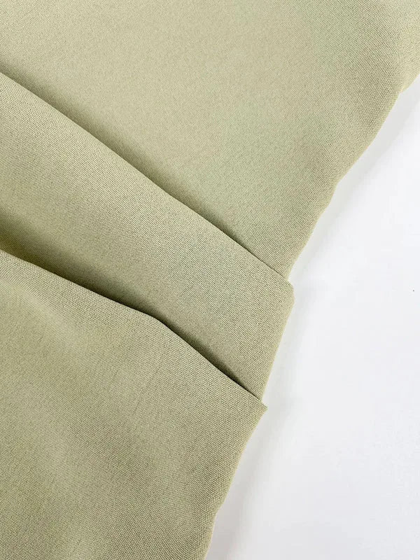 Close-up of the folded sage green fabric showing its smooth woven texture and matte finish