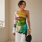 Close-up side angle highlighting the vivid yellow, green, blue and pink painterly print and the long draped sleeve against the white A-line fabric.